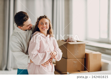 Happy young family couple man and woman hugging after moving cardboard boxes to their new apartment Happy young family couple man and woman hugging after moving cardboard boxes to their new apartment 142481615