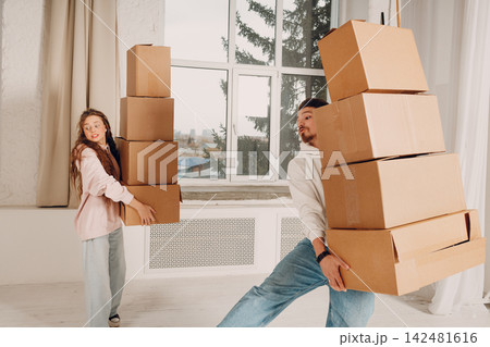 Happy young family couple man and woman moving with cardboard boxes to new estate home apartment Happy young family couple man and woman moving with cardboard boxes to new estate home apartment 142481616