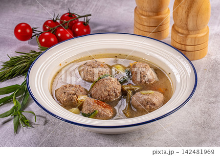 Homemade meatball soup with fresh vegetables in white bowl with cherry tomatoes and rosemary 142481969