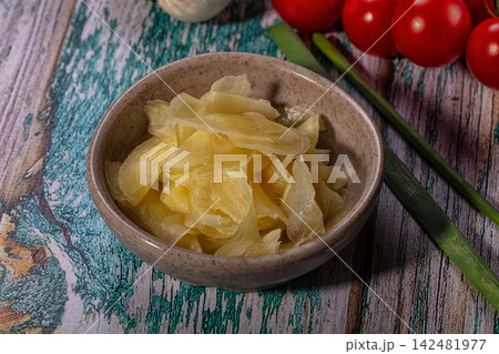Pickled ginger in a ceramic bowl with fresh vegetables on a rustic wooden table Pickled ginger in a ceramic bowl with fresh vegetables on a rustic wooden table 142481977