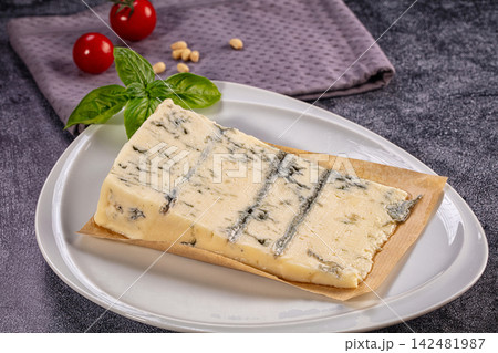 Gorgonzola cheese wedge on white plate with basil and tomatoes 142481987