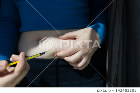 Woman making hormone injection into belly at home for ivf fertility treatment and ovulation stimulation. Concept of reproductive medicine, hormone therapy, and subcutaneous injection. 142482185