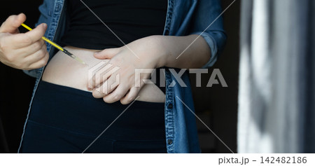 Woman making hormone injection into belly at home for ivf fertility treatment and ovulation stimulation. Concept of reproductive medicine, hormone therapy, and subcutaneous injection. 142482186