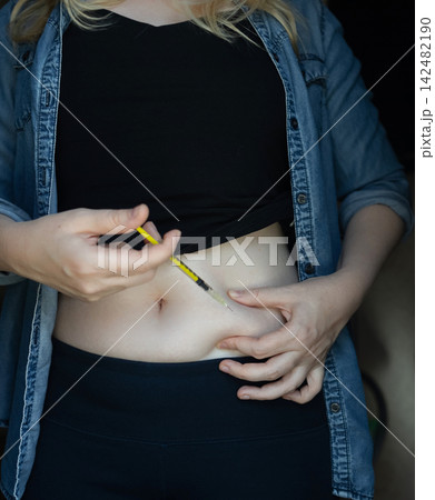 Woman making hormone injection into belly at home for ivf fertility treatment and ovulation stimulation. Concept of reproductive medicine, hormone therapy, and subcutaneous injection. Woman making hormone injection into belly at home for ivf fertility treatment and ovulation stimulation. Concept of reproductive medicine, hormone therapy, and subcutaneous injection. 142482190