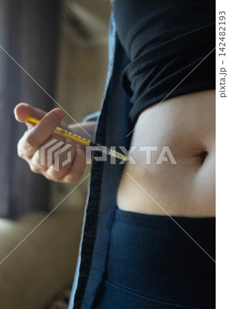 Woman making hormone injection into belly at home for ivf fertility treatment and ovulation stimulation. Concept of reproductive medicine, hormone therapy, and subcutaneous injection. 142482193