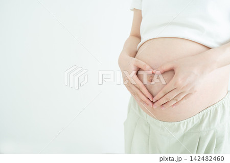 Pregnant woman make her hands in heart shape on big tummy. Pregnancy and maternity concept. Mom with love, wellness, healthy and tenderness. Pregnant woman make her hands in heart shape on big tummy. Pregnancy and maternity concept. Mom with love, wellness, healthy and tenderness. 142482460