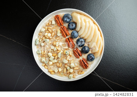 Oatmeal. Bowl of oatmeal porridge with blackberry, bananas and chia seeds on gray concrete old table background. Top view in flat lay style. Natural ingredients. Hot healthy breakfast and diet food 142482831