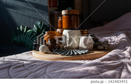 Amber Jars with Wooden Lids on Bed. Amber Candles Glass Jars and Bottles with Natural Elements 142483451