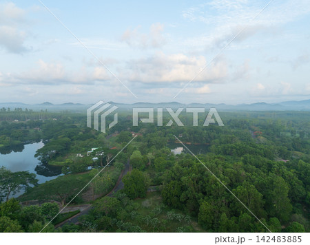 Aerial view of tropical forest with freshwater ponds and mountains. Rural ecosystem and natural landscape during green season. Natural habitat, freshwater resources and environmental conservation. Aerial view of tropical forest with freshwater ponds and mountains. Rural ecosystem and natural landscape during green season. Natural habitat, freshwater resources and environmental conservation. 142483885