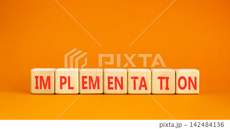 Implementation word symbol. Concept word Implementation on beautiful wooden blocks. Beautiful orange table orange background. Business implementation word concept. Copy space. Implementation word symbol. Concept word Implementation on beautiful wooden blocks. Beautiful orange table orange background. Business implementation word concept. Copy space. 142484136
