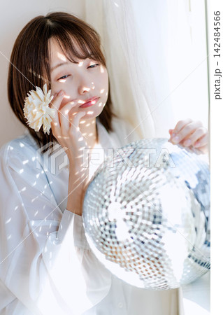 白い花を耳に添え物憂げな表情を見せる白ブラウスの女性 白い花を耳に添え物憂げな表情を見せる白ブラウスの女性 142484566