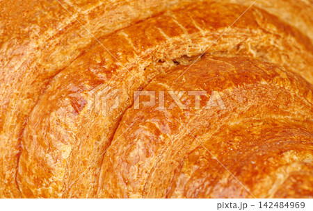 Mouth-watering golden croissant crust close up. Freshly baked artisan pastry with flaky texture. 142484969