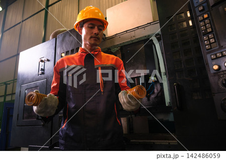 The engineer checks the parts coming out of the machine. 142486059