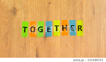 Together word symbol. Concept word Together on beautiful colored papers. Beautiful wooden background. Business support help together word concept. Copy space. Together word symbol. Concept word Together on beautiful colored papers. Beautiful wooden background. Business support help together word concept. Copy space. 142486541