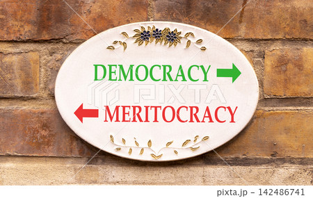 Democracy or meritocracy words symbol. Concept words Democracy Meritocracy on beautiful white sign plate. Beautiful brick wall background. Business democracy meritocracy concept. Copy space Democracy or meritocracy words symbol. Concept words Democracy Meritocracy on beautiful white sign plate. Beautiful brick wall background. Business democracy meritocracy concept. Copy space 142486741