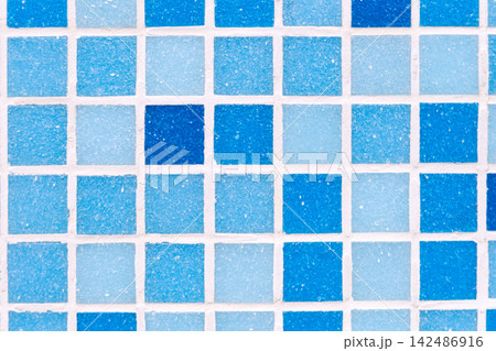 Mosaic blue tiles displaying varying shades of color and grainy texture, creating a geometric grid pattern with white grout lines, useful as a decorative surface or background 142486916
