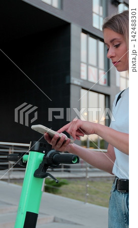 Vertical video. Woman scanning qr code on electric scooter, rental service app. Alternative transportation in city. Vertical video. Woman scanning qr code on electric scooter, rental service app. Alternative transportation in city. 142488301