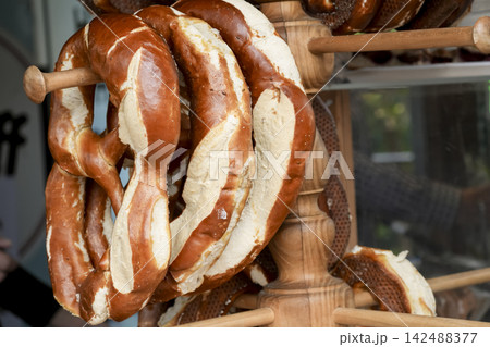 Fresh pretzels hanging on a wooden stand in a bakery, illustrating traditional Oktoberfest food culture. 142488377