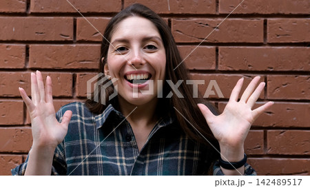 A surprised, delighted woman. An impressed woman tries to attract attention. Sales concept, a compelling offer. An enthusiastic girl against a brick wall. A surprised, delighted woman. An impressed woman tries to attract attention. Sales concept, a compelling offer. An enthusiastic girl against a brick wall. 142489517