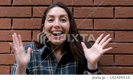 A surprised, delighted woman. An impressed woman tries to attract attention. Sales concept, a compelling offer. An enthusiastic girl against a brick wall. A surprised, delighted woman. An impressed woman tries to attract attention. Sales concept, a compelling offer. An enthusiastic girl against a brick wall. 142489518