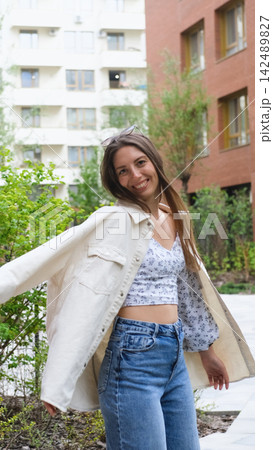 An attractive woman with a beautiful smile and long hair is spinning, walking around the city, posing for the camera. An attractive woman with a beautiful smile and long hair is spinning, walking around the city, posing for the camera. 142489827