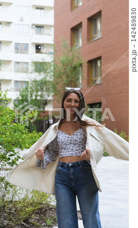An attractive woman with a beautiful smile and long hair is spinning, walking around the city, posing for the camera. An attractive woman with a beautiful smile and long hair is spinning, walking around the city, posing for the camera. 142489830