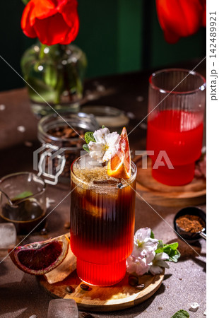 Refreshing iced coffee with blood orange and flower garnish Refreshing iced coffee with blood orange and flower garnish 142489921