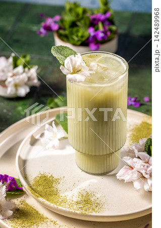 Iced matcha latte decorated with mint and flowers on table Iced matcha latte decorated with mint and flowers on table 142489968
