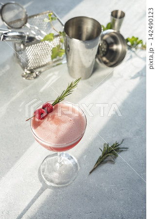 Refreshing pink cocktail garnished with raspberries and rosemary 142490123
