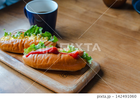 木のボードに盛り付けられたホットドッグとコーヒーの軽食 木のボードに盛り付けられたホットドッグとコーヒーの軽食 142491060