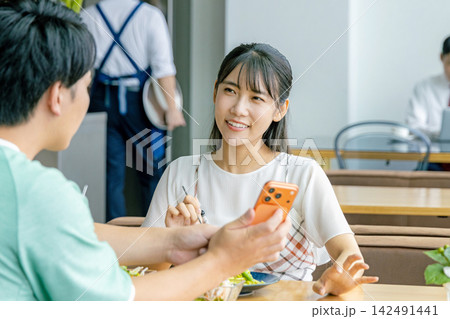 カフェでスマホを見る若いカップル カフェでスマホを見る若いカップル 142491441