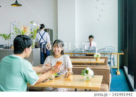 カフェでスマホを見る若いカップル 142491442
