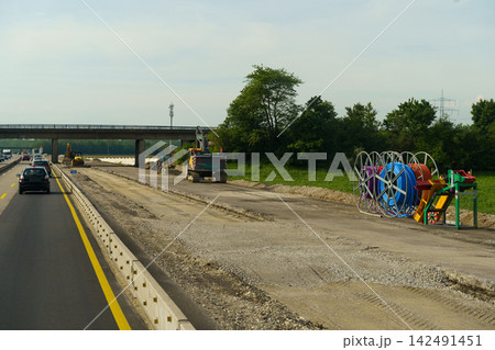 Busy construction zone showcases colorful equipment by the road under the sun Busy construction zone showcases colorful equipment by the road under the sun 142491451