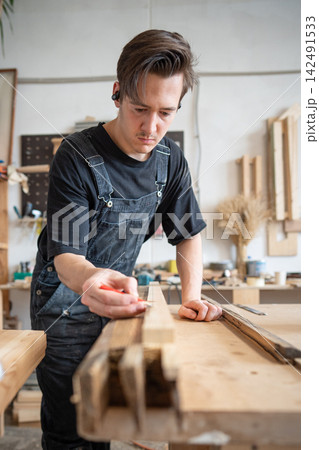 Qualified master restorer preparing patch for old window frame at workbench in restoration studio. 142491533
