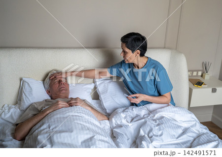 Worried woman check fever of sick partner in bed using thermometer. Illness care, high temperature Worried woman check fever of sick partner in bed using thermometer. Illness care, high temperature 142491571