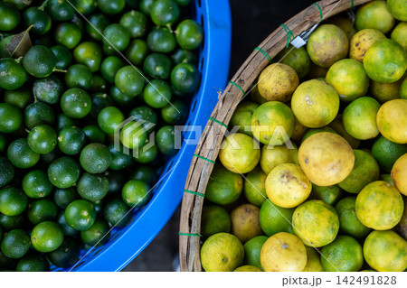 Street food market selling various kinds of citruses, baskets with fresh ripe green and yellow limes Street food market selling various kinds of citruses, baskets with fresh ripe green and yellow limes 142491828