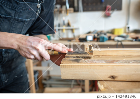 Wooden board preparation process for restoration in carpentry workshop, master chisels wood surface. Wooden board preparation process for restoration in carpentry workshop, master chisels wood surface. 142491846
