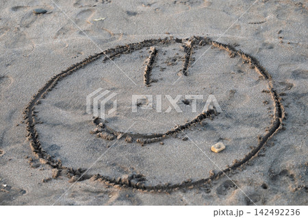 Smiley face drawn in the sand on a beach during daytime Smiley face drawn in the sand on a beach during daytime 142492236