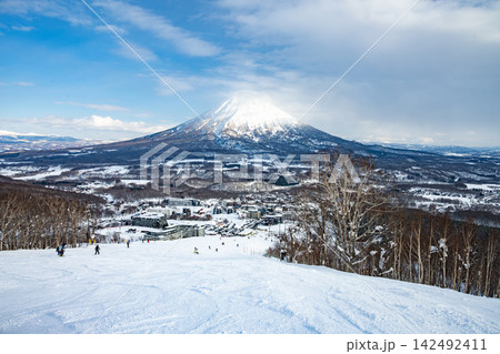 冬の北海道ニセコアンヌプリのスキー場ゲレンデから望む雪化粧した羊蹄山とスキーヤー 142492411