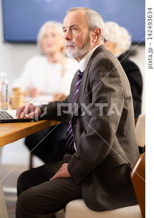 Office coworkers watching presentation while sitting at table with laptop, notes 142493634