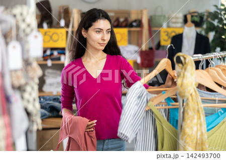 Young woman customer elect something summer clothes in store. 142493700
