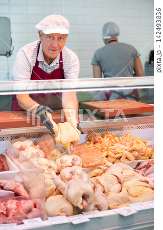 Adult man seller lays out chicken in butcher shop 142493836