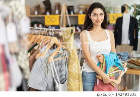 Woman on sale choosing dresses and tops in the store Woman on sale choosing dresses and tops in the store 142493838