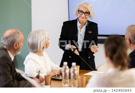 Woman manager holding business meeting with colleagues at table in office Woman manager holding business meeting with colleagues at table in office 142493843