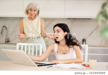 Elderly woman quarrels with young woman working at laptop Elderly woman quarrels with young woman working at laptop 142493994