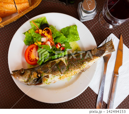 Grilled seabass accompanied by colorful fresh vegetable salad 142494153