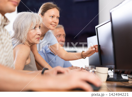 Woman teacher helping elderly people learn how to use computer 142494221