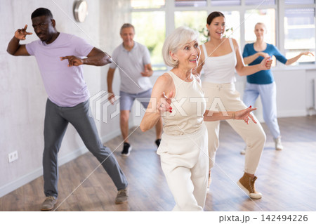 Female instructor teaches senior students of different ages basic movements of contemporary dances Female instructor teaches senior students of different ages basic movements of contemporary dances 142494226