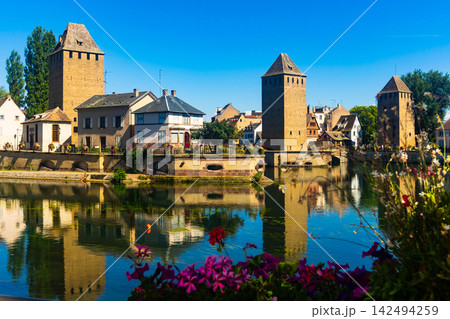 Strasbourg, France. Barrage Vauban scenic river and architecture view on bridge Ponts Couverts with flowers Strasbourg, France. Barrage Vauban scenic river and architecture view on bridge Ponts Couverts with flowers 142494259