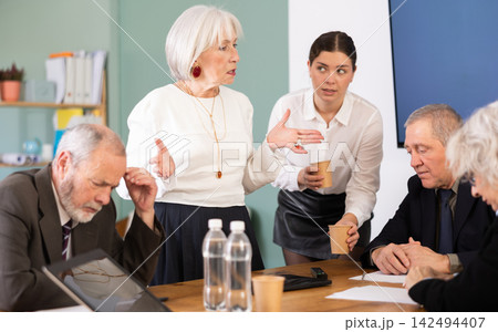 Businessman of a large company scolds his employees sitting at workdesk in office 142494407